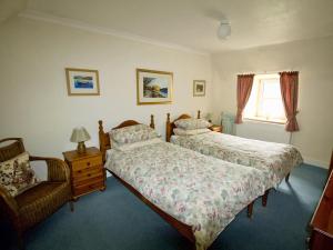 a bedroom with two beds and a chair and a window at Coelard Farmhouse - Usj in Appin