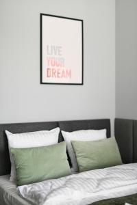 a bed with green pillows and a framed picture at Mini Apartamenty Poznań in Poznań