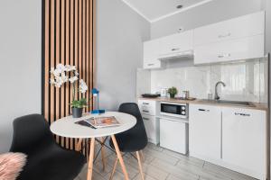 a kitchen with white cabinets and a table and chairs at Mini Apartamenty Poznań in Poznań