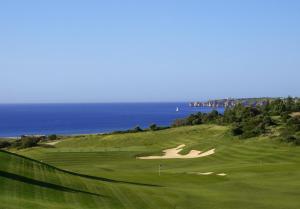 a green golf course with the ocean in the background at Palmares Beach House Hotel - Adults Only in Lagos