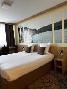 a hotel room with a large bed with a view of the water at Brit Hotel Montargis in Mormant-sur-Vernisson