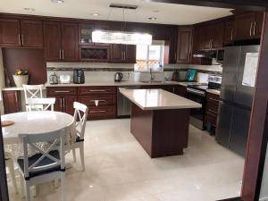 a kitchen with wooden cabinets and a table and a table and chairs at As You Wish Suites & Rooms Near YVR with Parking in Richmond +14 photos