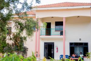a white house with two people sitting on a porch at Jojos Palace Hotel - Gulu in Gulu