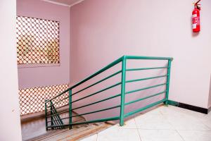 a staircase with a green rail in a room with a window at Jojos Palace Hotel - Gulu in Gulu