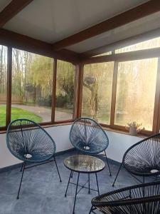 three chairs and a table in a screened in porch at Gîte du Trempal in Audruicq