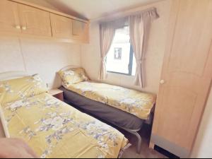a small bedroom with two beds in a caravan at VJ Plum a 2 bed 6 berth luxury static caravan, bedding Included, on Coral Beach in Ingoldmells in Ingoldmells