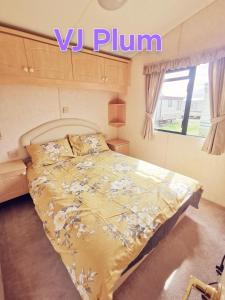 a bedroom with a bed with a yellow comforter and a window at VJ Plum a 2 bed 6 berth luxury static caravan, bedding Included, on Coral Beach in Ingoldmells in Ingoldmells