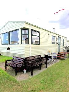 a yellow caravan with a table and benches in front of it at VJ Plum a 2 bed 6 berth luxury static caravan, bedding Included, on Coral Beach in Ingoldmells in Ingoldmells