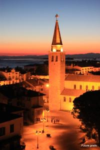 a building with a tower with a cross on top of it at San Pietro D'Orio Apartment in Grado