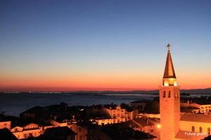 a church steeple with a cross on top at sunset at San Pietro D'Orio Apartment in Grado