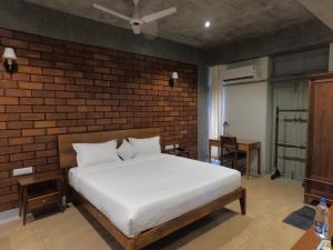 a bedroom with a white bed and a brick wall at Savana Luxury Stay in Pondicherry
