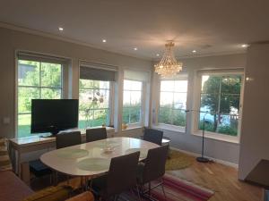 a dining room with a table and a tv and windows at Workers Stay - Temporary House Umeå in Umeå