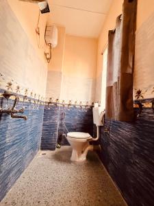 a bathroom with a toilet and a blue tiled wall at Kusum Nest in Shillong