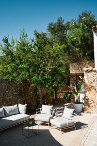 a patio with white couches and tables and trees at El Convento de Biniamar in El Port de la Selva
