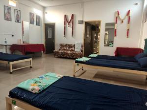 a room with two beds and a table and chairs at Green bell male dormitory in Bhopal
