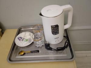 a tray with a coffee maker and glasses on it at Bodomzor Family Hotel in Salor Bekati