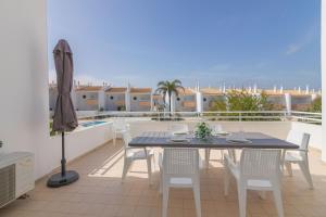 a table and chairs on a balcony with an umbrella at Aldeamento Turistico Aldeia da Galé in Albufeira