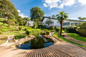 a garden with a pond in front of a building at Fazenda Santanna Hotel in Amparo