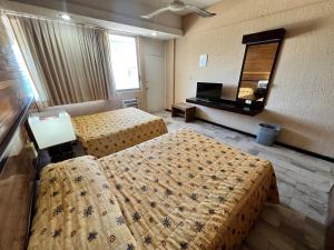 a hotel room with two beds and a mirror at Hotel De Cima Beach Club in Mazatlán