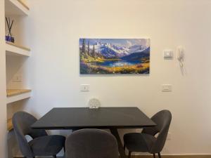 a dining room table with chairs and a painting on the wall at Bilocale accogliente in centro Aprica in Aprica