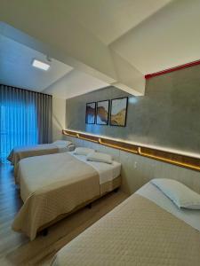 a hotel room with three beds and two windows at Oceano Hotel de Barra Velha in Barra Velha