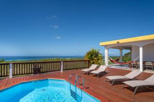 a swimming pool on a deck with chairs and the ocean at Villa O'Bed in Grand-Bourg