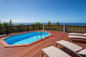 a deck with a swimming pool and chairs on it at Villa O'Bed in Grand-Bourg