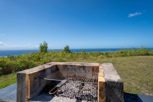 a grill on a hill with the ocean in the background at Villa O'Bed in Grand-Bourg