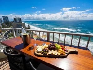 a plate of food on a table on a balcony with the ocean at Absolute Beachfront Ocean Balcony Heated Pool in Gold Coast