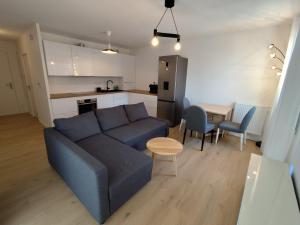 a living room with a blue couch and a kitchen at Chez Mika in Linxe