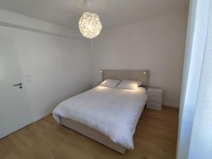 a bedroom with a white bed and a chandelier at Chez Mika in Linxe +26 photos