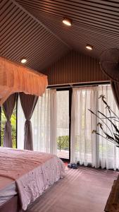 a bedroom with a bed and large windows at Lilys Stone Garden Bungalow in Tram de Dak Mil