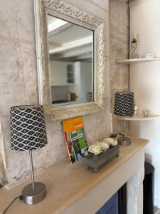 a mirror on top of a fireplace with two lamps at Maison bord de sèvre in Coulon +30 photos
