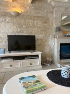 a living room with a television and a book on a table at Maison bord de sèvre in Coulon