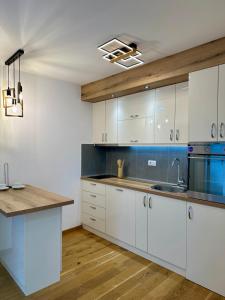 a kitchen with white cabinets and a wooden floor at VIP House 5 in Vrnjačka Banja