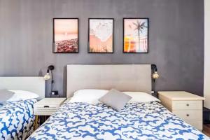 a bedroom with two beds and four pictures on the wall at Luminoso Appartamento con Balcone & ParcheggioFree in La Spezia