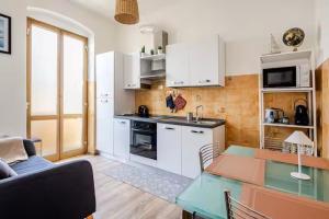 a kitchen with white cabinets and a table in a room at Luminoso Appartamento con Balcone & ParcheggioFree in La Spezia