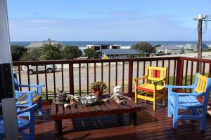 a deck with three chairs and a table with a view of the ocean at The Wilderness Way in Wilderness
