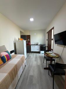 a bedroom with a bed and a table and a kitchen at Espaço Parque das Gaivotas in Vila Velha