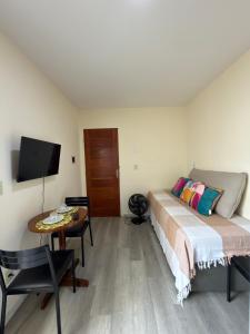 a bedroom with a bed and a table and a tv at Espaço Parque das Gaivotas in Vila Velha