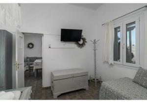a living room with a tv on a white wall at Stella's Mandrakia Seaside House in Mandrakia