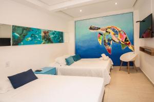 a room with two beds and a painting of a fish at Hotel Barahona Cartagena in Cartagena de Indias