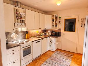a kitchen with white cabinets and a wooden floor at Cozy Summerhouse by the River with free BIKES and ping pong in Rovaniemi