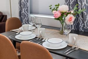 a table with plates and glasses and a vase of flowers at Endless Sunset- Near Beach Surf and Pet Friendly in Huntington Beach