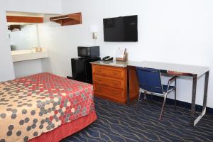 a room with a desk and a bed and a desk with a computer at Crossroads Inn in Fort Pierce