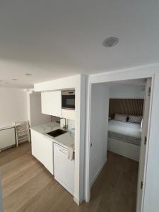 a small white kitchen with a bed in the background at Marina Rey Aparthotel Playa de Puerto Rey in Vera