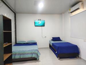 a room with two beds and a tv on the wall at Apartaestudio Marbella #2-10 in Cartagena de Indias