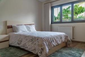 a bedroom with a bed with a white comforter and two windows at Casa do Paçô - Cabeceiras de Basto in Cabeceiras de Basto