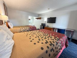 a hotel room with two beds and a flat screen tv at Crossroads Inn in Fort Pierce