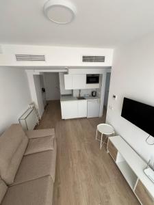 a living room with a couch and a tv at Marina Rey Aparthotel Playa de Puerto Rey in Vera